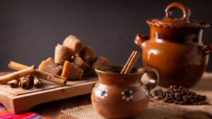 This is an image showing a cup of café that was made in the olla (ceramic pot) behind it.